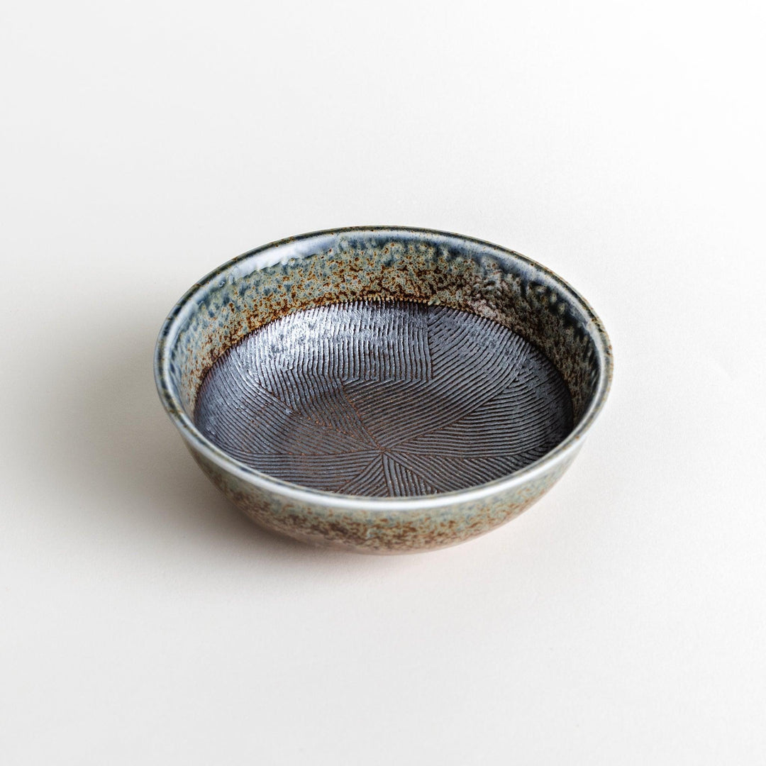 A cereal bowl with a textured glaze in blue, brown, and cream tones, featuring a ridged interior.