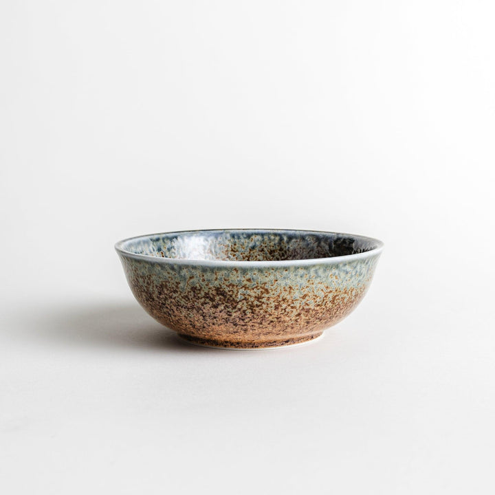 A cereal bowl with a textured glaze in blue, brown, and cream tones, featuring a ridged interior.