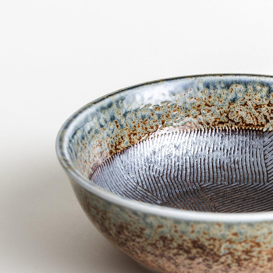 A cereal bowl with a textured glaze in blue, brown, and cream tones, featuring a ridged interior.