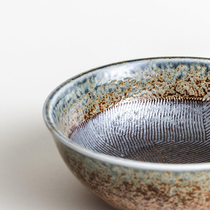 A cereal bowl with a textured glaze in blue, brown, and cream tones, featuring a ridged interior.