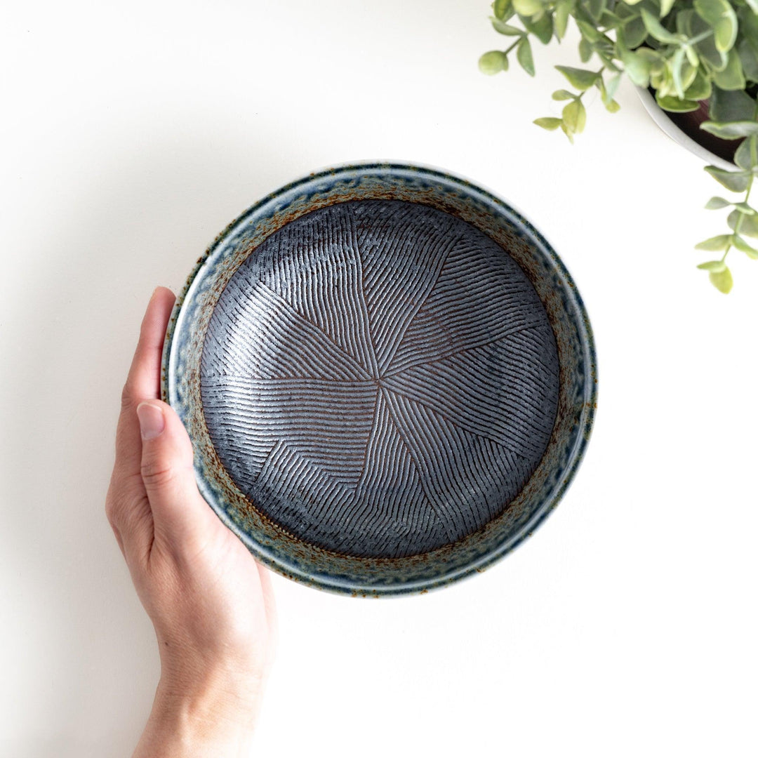 A cereal bowl with a textured glaze in blue, brown, and cream tones, featuring a ridged interior.