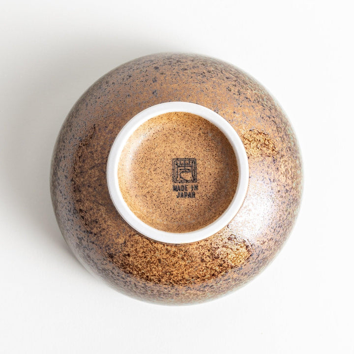 A bowl with a textured glaze featuring a mix of blue, brown, and cream colors with a ridged interior.