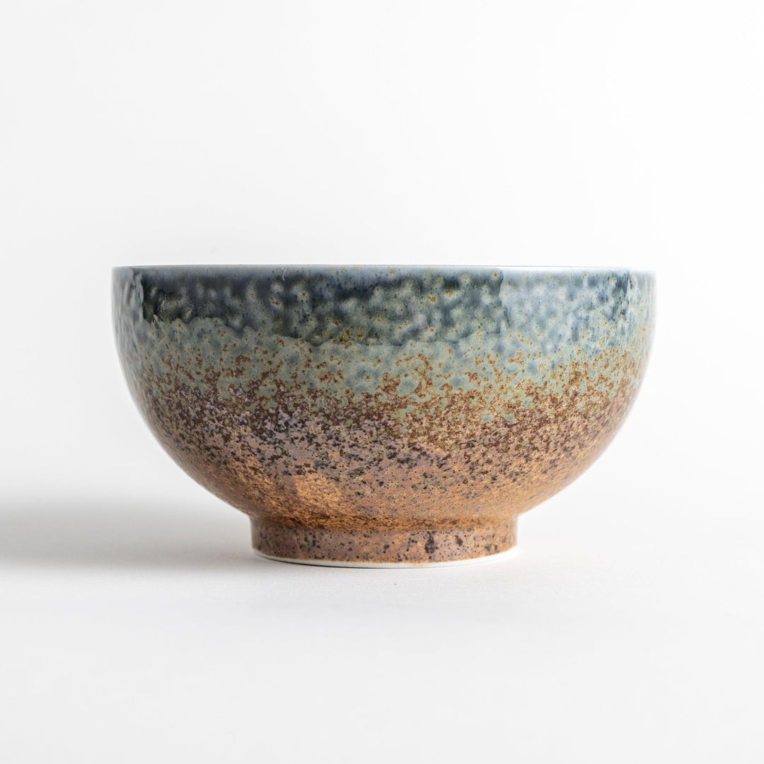 A bowl with a textured glaze featuring a mix of blue, brown, and cream colors with a ridged interior.