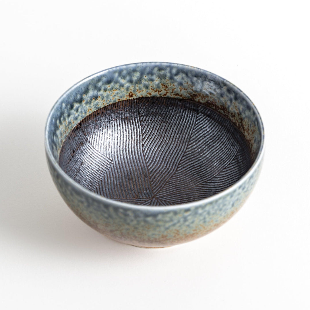 A bowl with a textured glaze featuring a mix of blue, brown, and cream colors with a ridged interior.