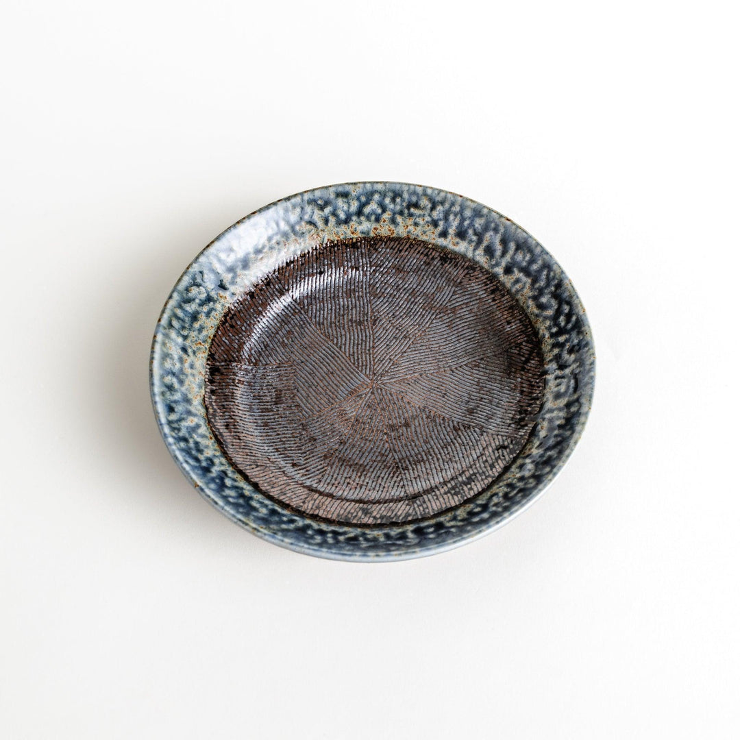 A pasta bowl with a textured glaze in blue, brown, and cream hues, featuring a ridged interior.