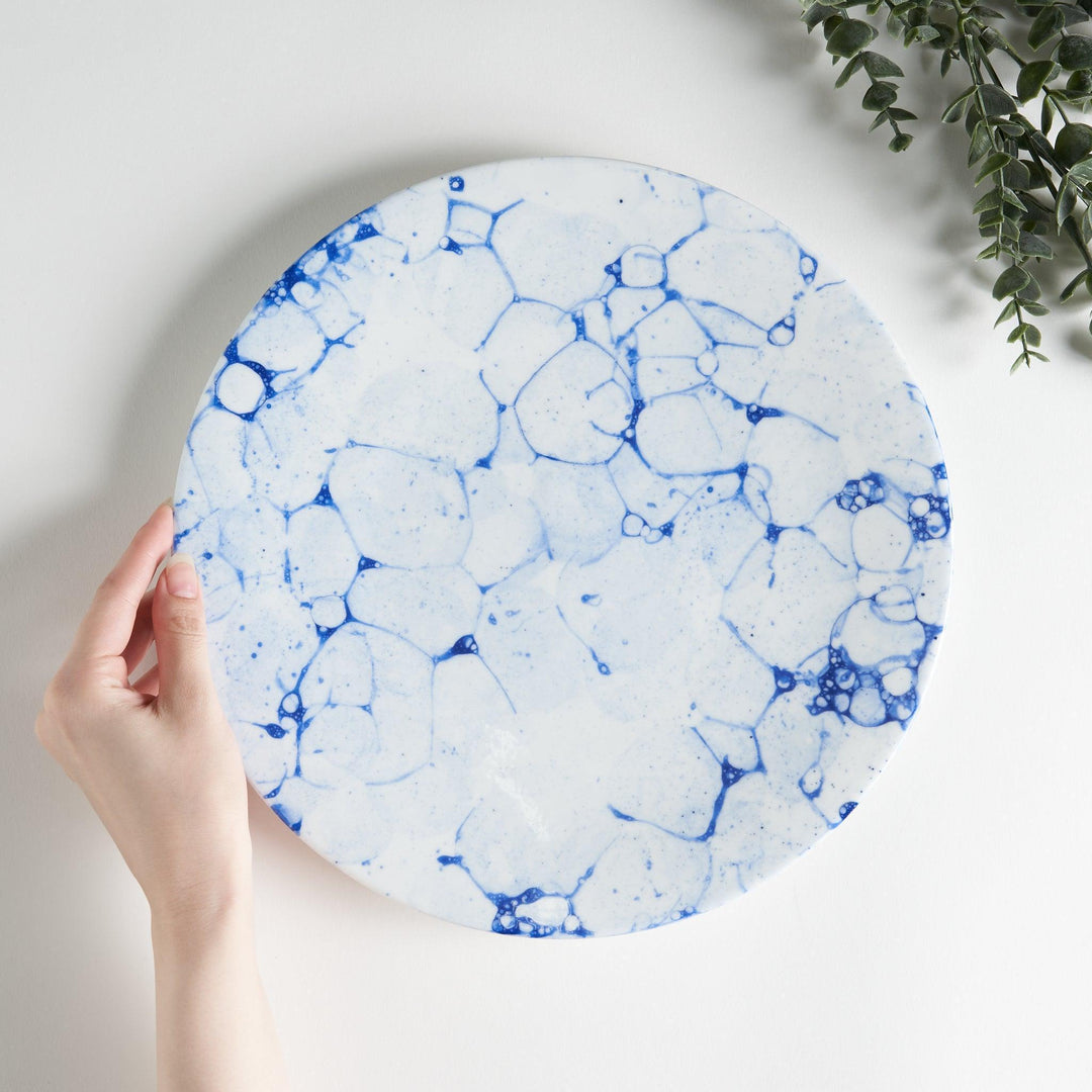 A round dinner plate with a blue bubble-like design on a white background.