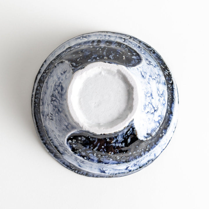 A bowl with a textured, uneven surface featuring blue and white glaze with an organic design.