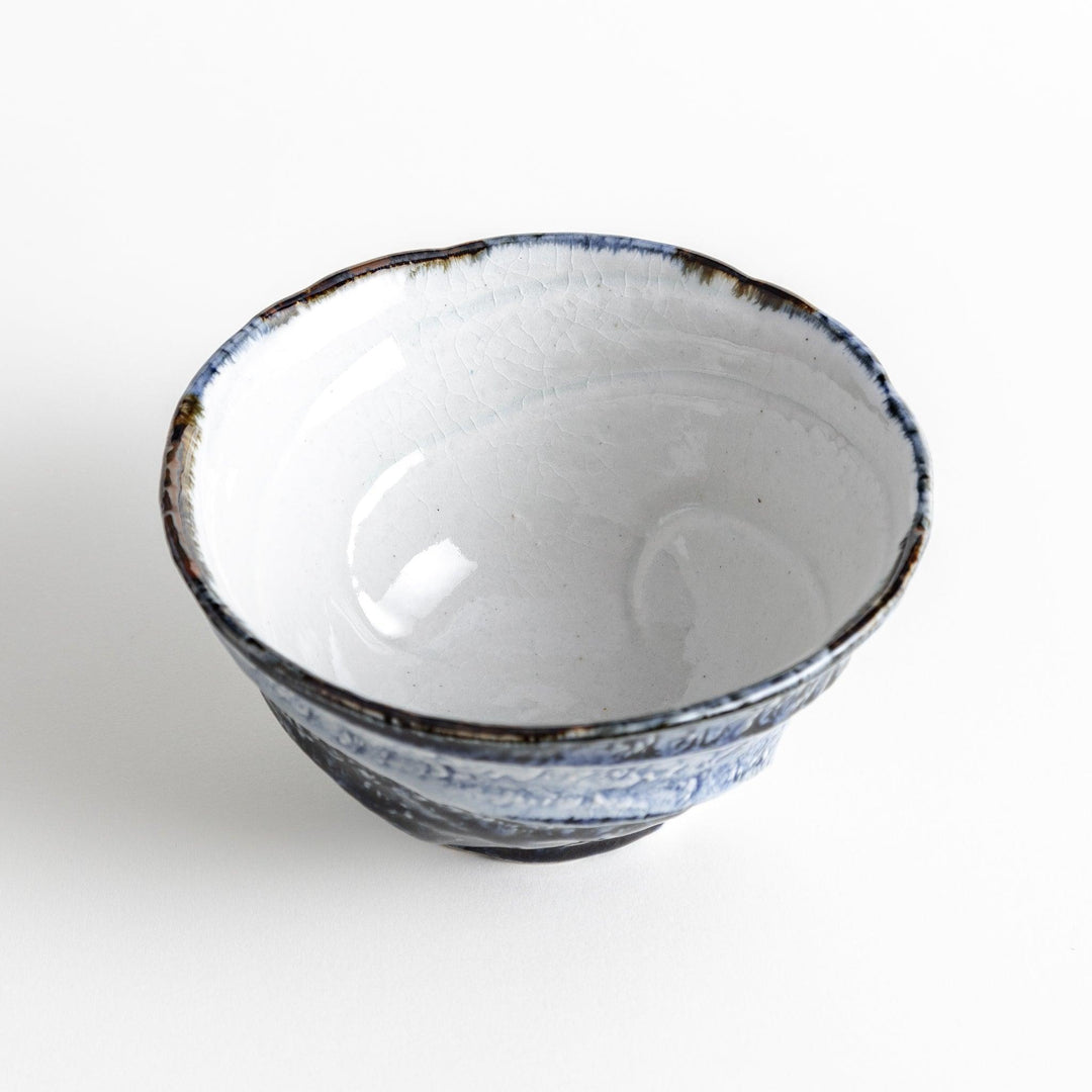 A bowl with a textured, uneven surface featuring blue and white glaze with an organic design.