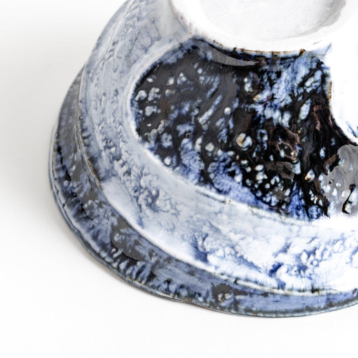 A bowl with a textured, uneven surface featuring blue and white glaze with an organic design.