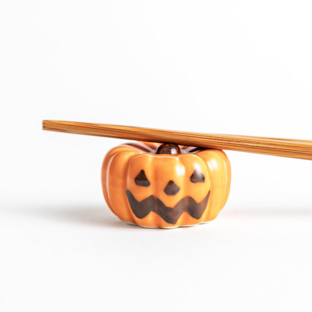 A ceramic chopstick rest resembling a jack-o-lantern.