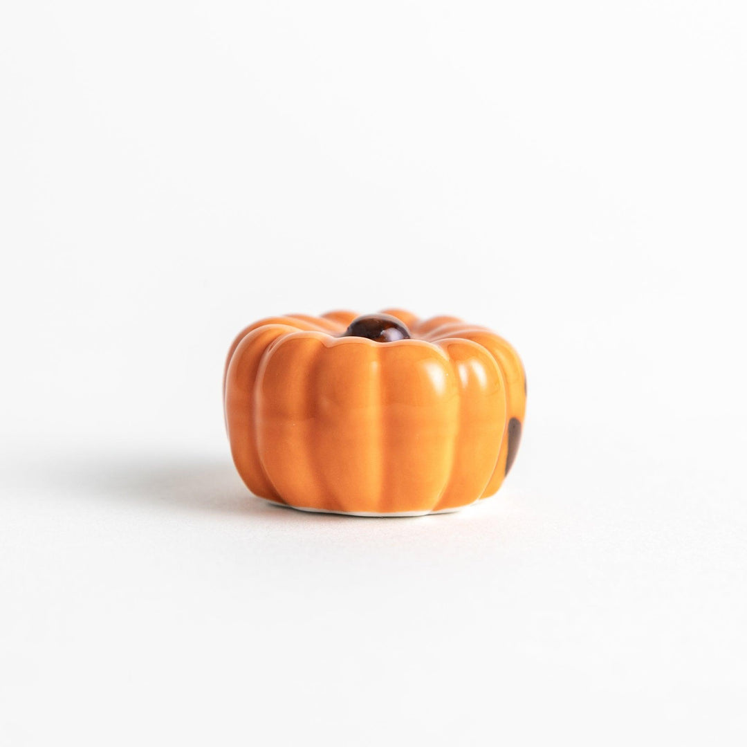 A ceramic chopstick rest resembling a jack-o-lantern.