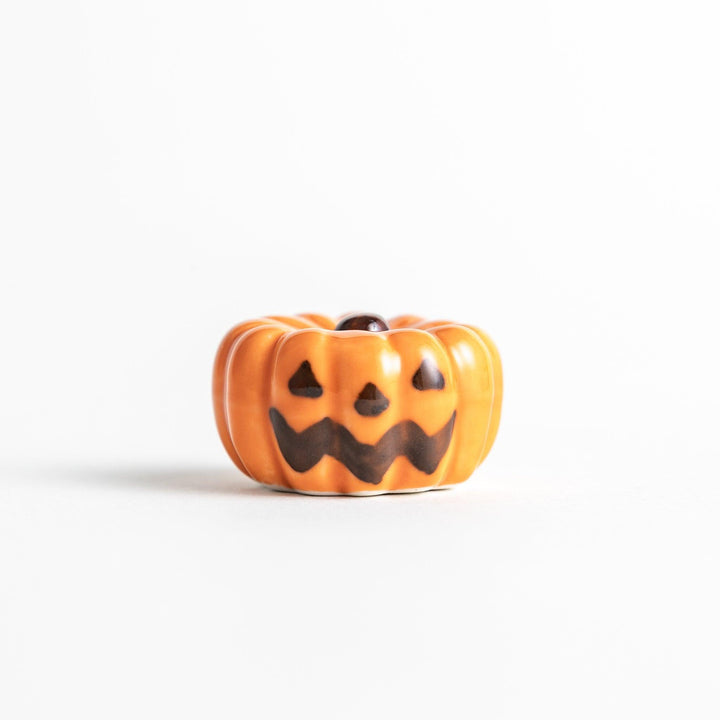 A ceramic chopstick rest resembling a jack-o-lantern.