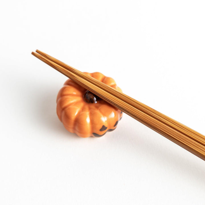 A ceramic chopstick rest resembling a jack-o-lantern.