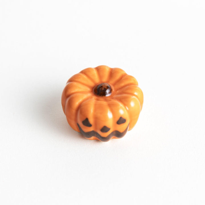 A ceramic chopstick rest resembling a jack-o-lantern.