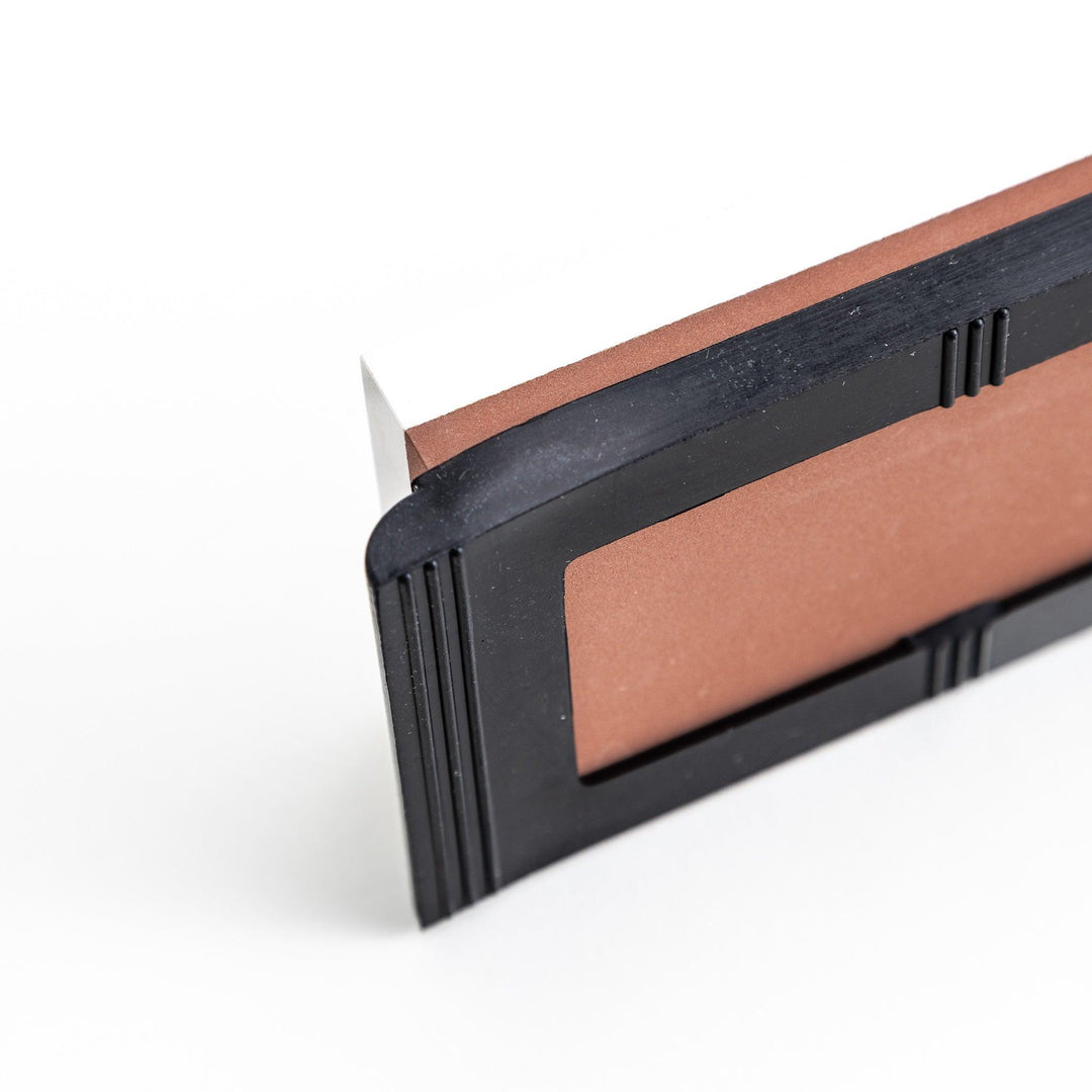 Rectangular sharpening stone with a brown surface and a black base, designed for honing knife blades.