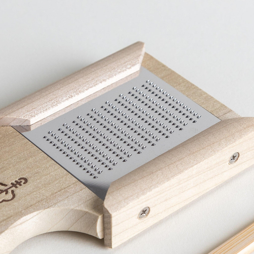 A stainless steel mini grater with a wooden handle