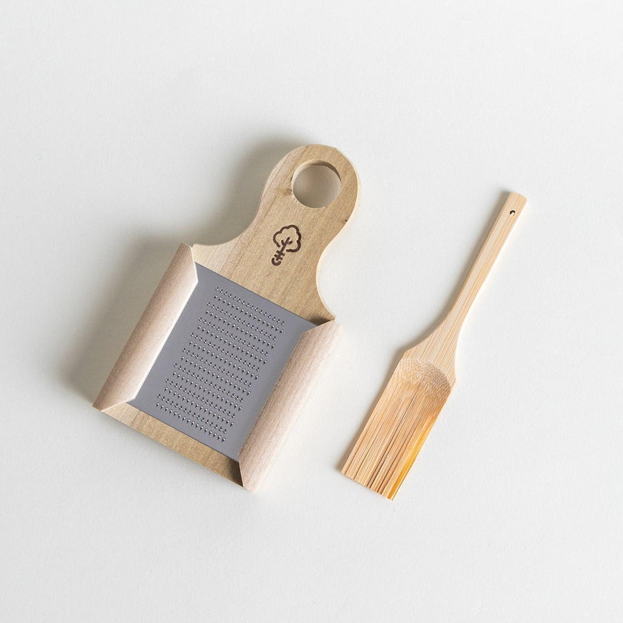 A stainless steel mini grater with a wooden handle