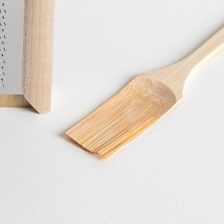 A stainless steel mini grater with a wooden handle