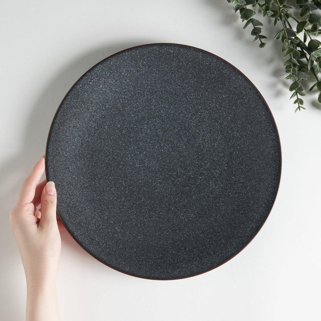 A round, matte black dinner plate with a smooth, understated design.