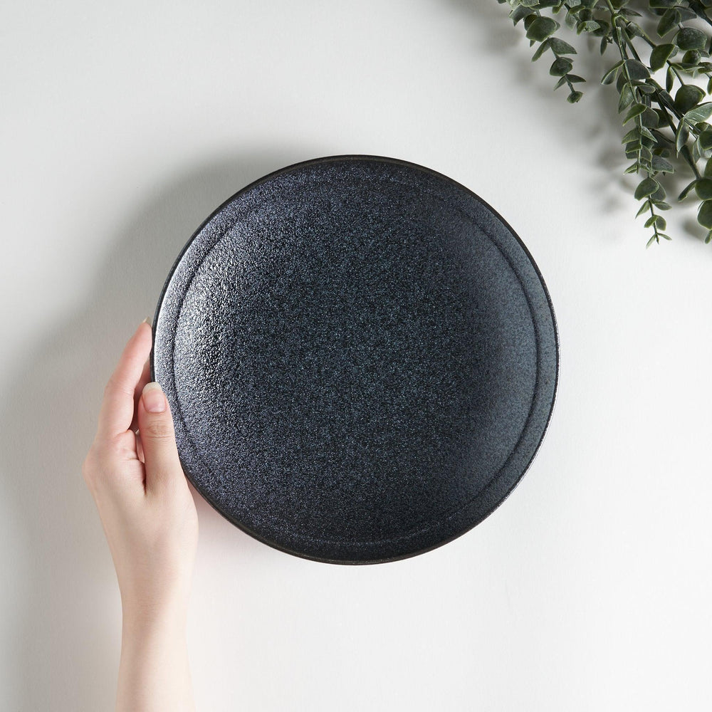 A round black salad plate with a subtle, rustic texture, ideal for modern table settings.