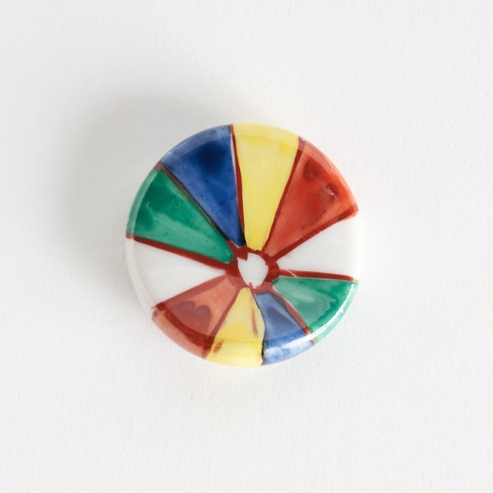 A colorful round ceramic chopstick rest with a pinwheel design.