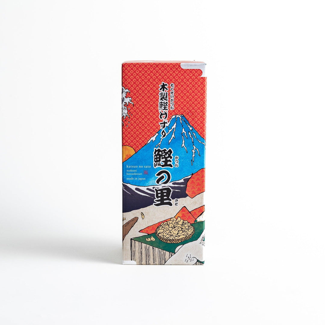 A large wooden box with a sliding drawer and lid, designed for shaving katsuobushi (dried bonito), with a colorful packaging box featuring traditional Japanese artwork.