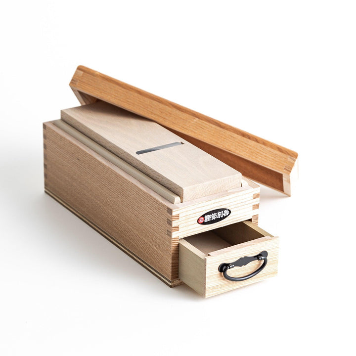 A large wooden box with a sliding drawer and lid, designed for shaving katsuobushi (dried bonito), with a colorful packaging box featuring traditional Japanese artwork.