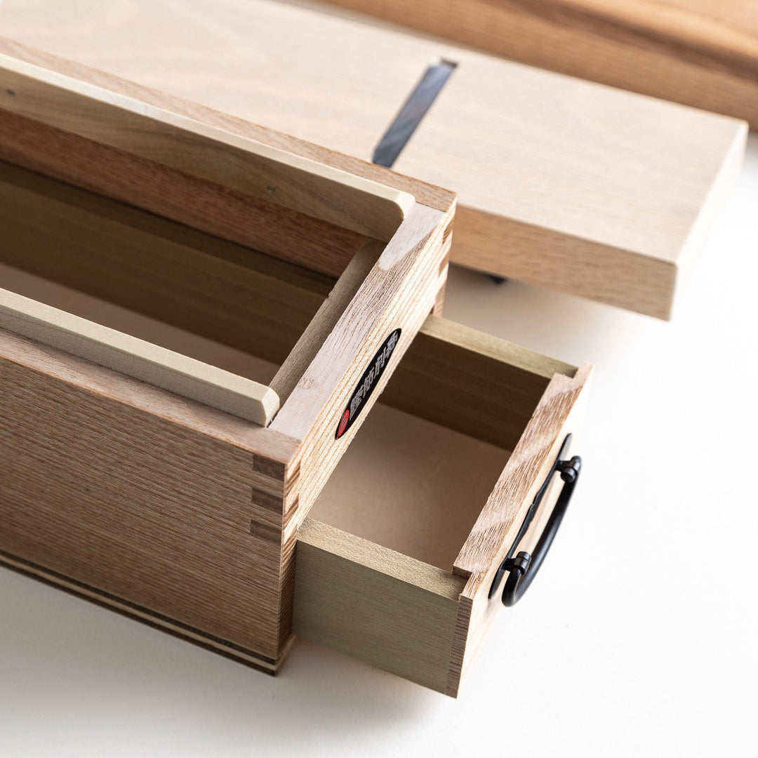 A large wooden box with a sliding drawer and lid, designed for shaving katsuobushi (dried bonito), with a colorful packaging box featuring traditional Japanese artwork.