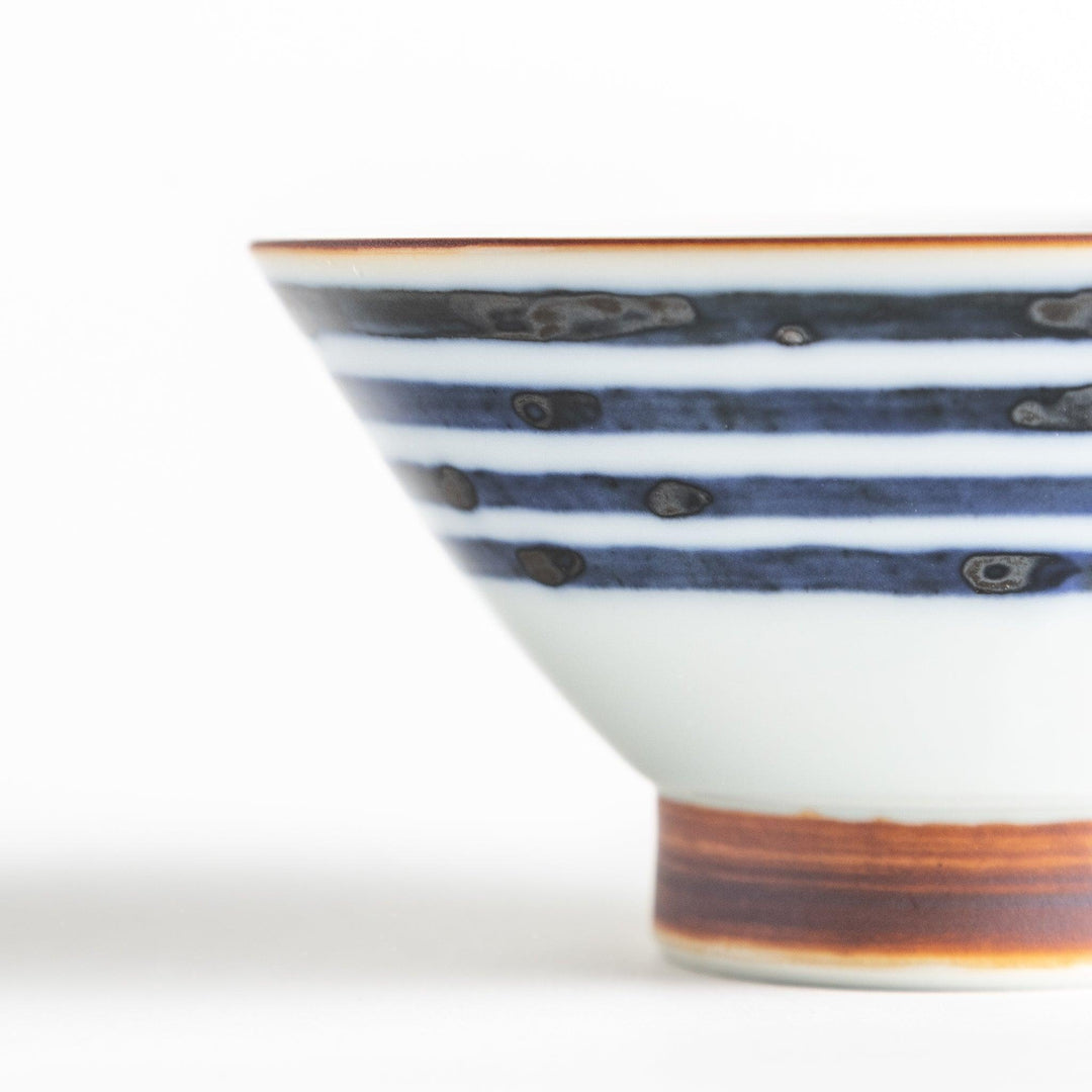 A white ceramic bowl with horizontal blue stripes and a brown rim.