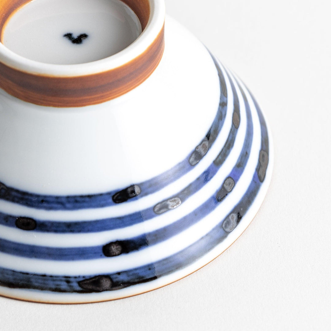 A white ceramic bowl with horizontal blue stripes and a brown rim.