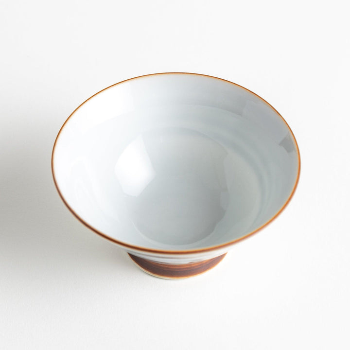 A white ceramic bowl with horizontal blue stripes and a brown rim.