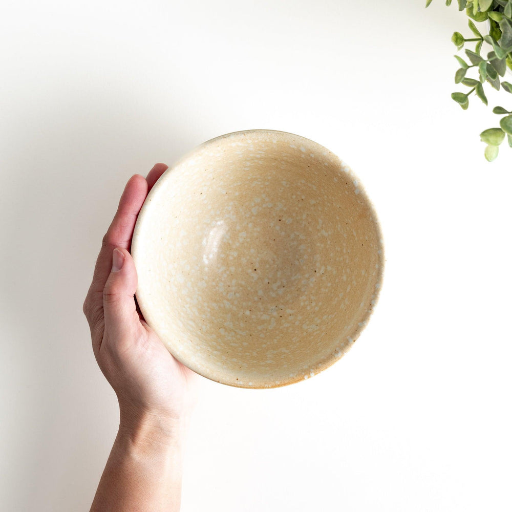 A beige ceramic rice bowl with a natural, rustic texture and a ribbed design.