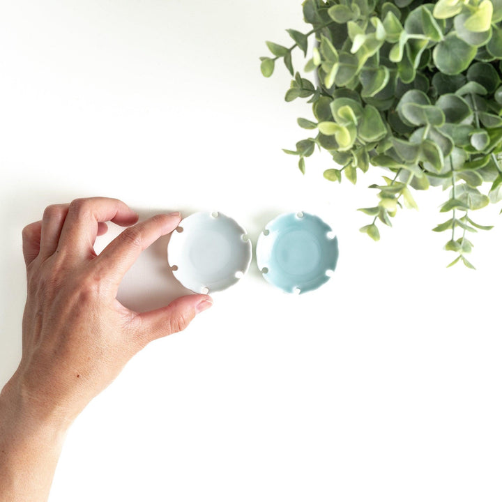 A set of small round gray and light blue ceramic chopstick rests with scalloped edges.