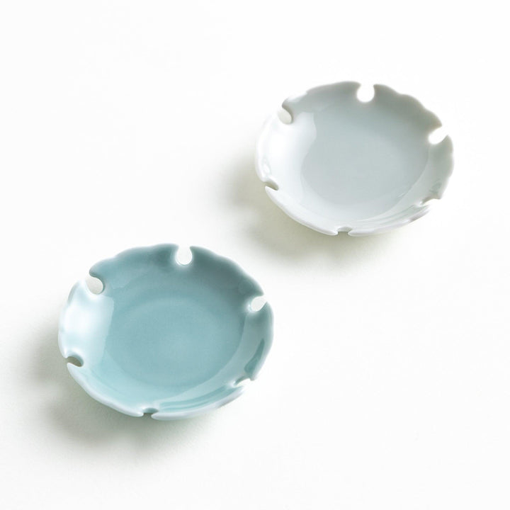 A set of small round gray and light blue ceramic chopstick rests with scalloped edges.