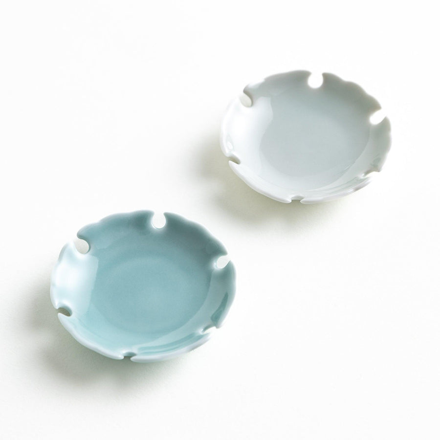 A set of small round gray and light blue ceramic chopstick rests with scalloped edges.