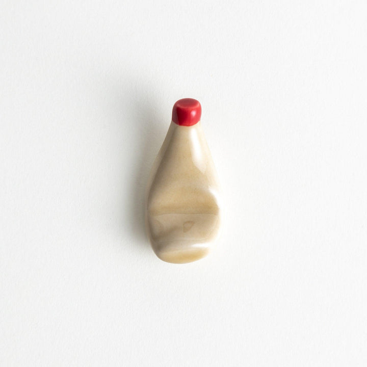 A ceramic chopstick rest resembling a mayonnaise bottle.