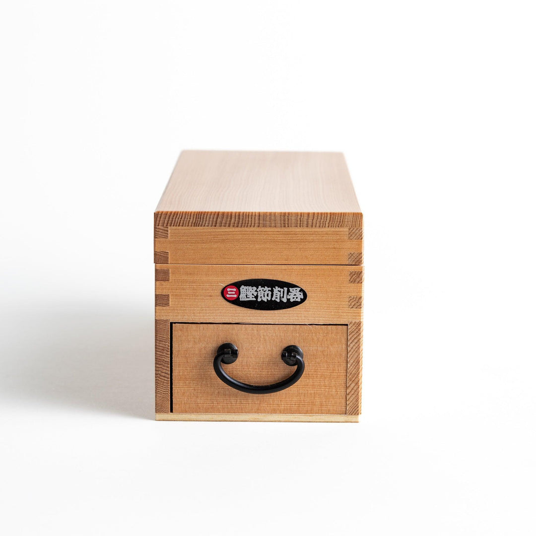 A medium-sized wooden box with a sliding drawer and lid, designed for shaving katsuobushi (dried bonito), with a colorful packaging box featuring traditional Japanese artwork.