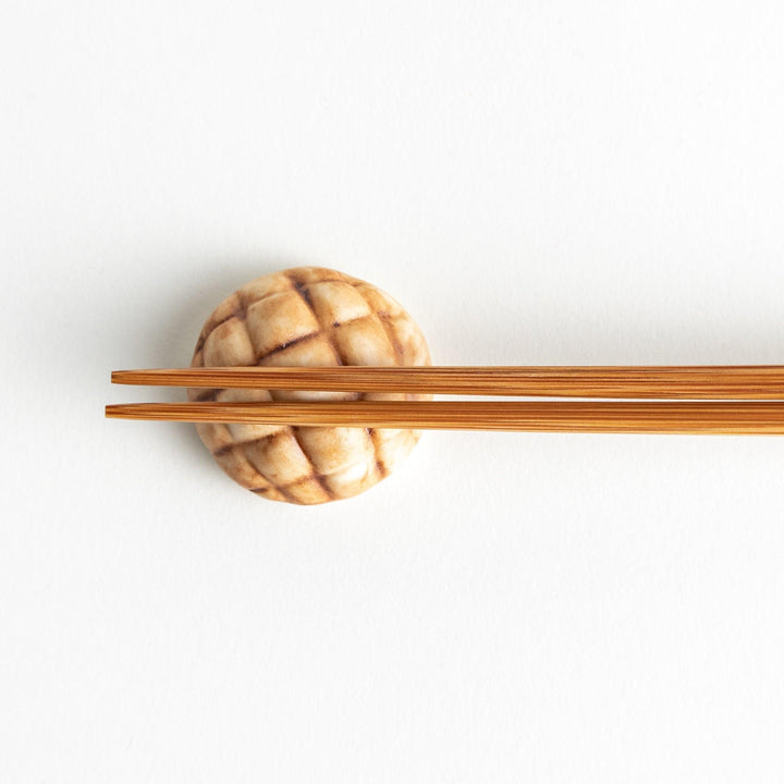 A ceramic chopstick rest resembling a Japanese melon pan bread.