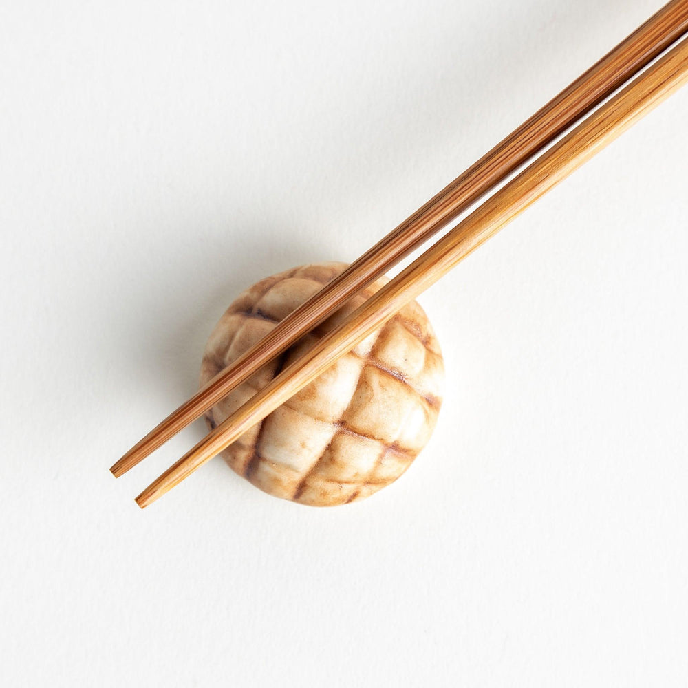 A ceramic chopstick rest resembling a Japanese melon pan bread.