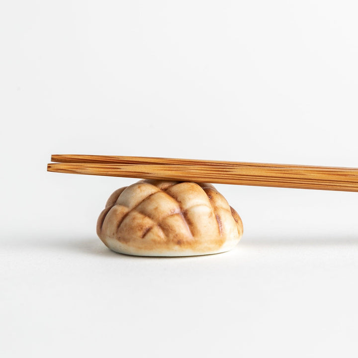 A ceramic chopstick rest resembling a Japanese melon pan bread.