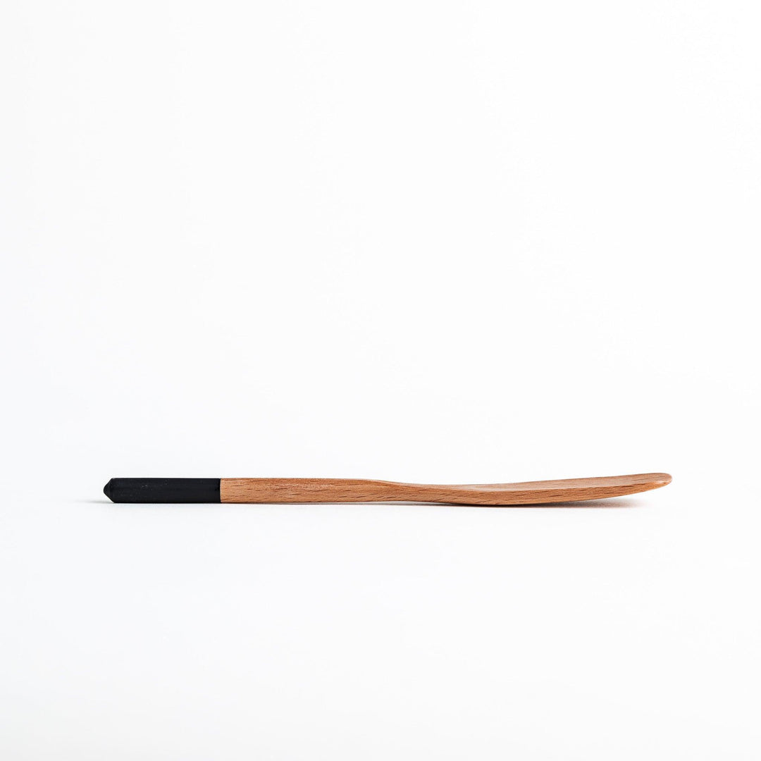 A set of four wooden spatulas with flat tips, each featuring a different colored end—white, black, blue, and red