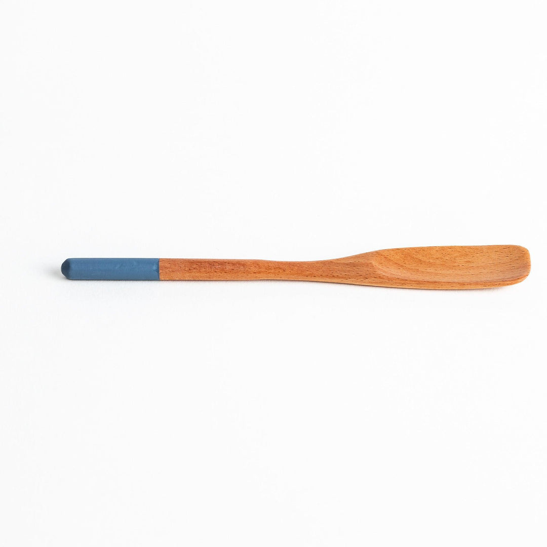 A set of four wooden spatulas with flat tips, each featuring a different colored end—white, black, blue, and red