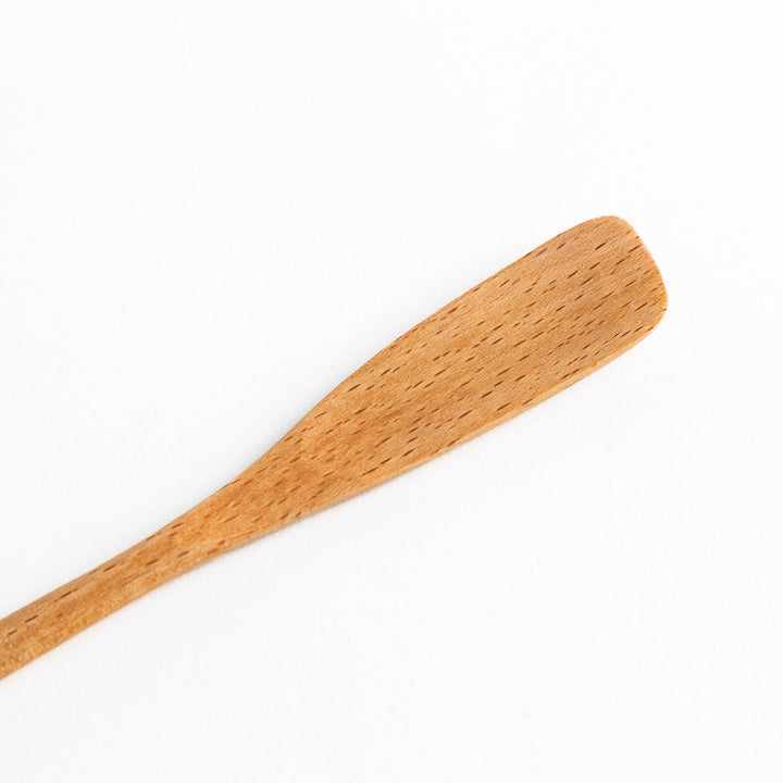 A set of four wooden spatulas with flat tips, each featuring a different colored end—white, black, blue, and red