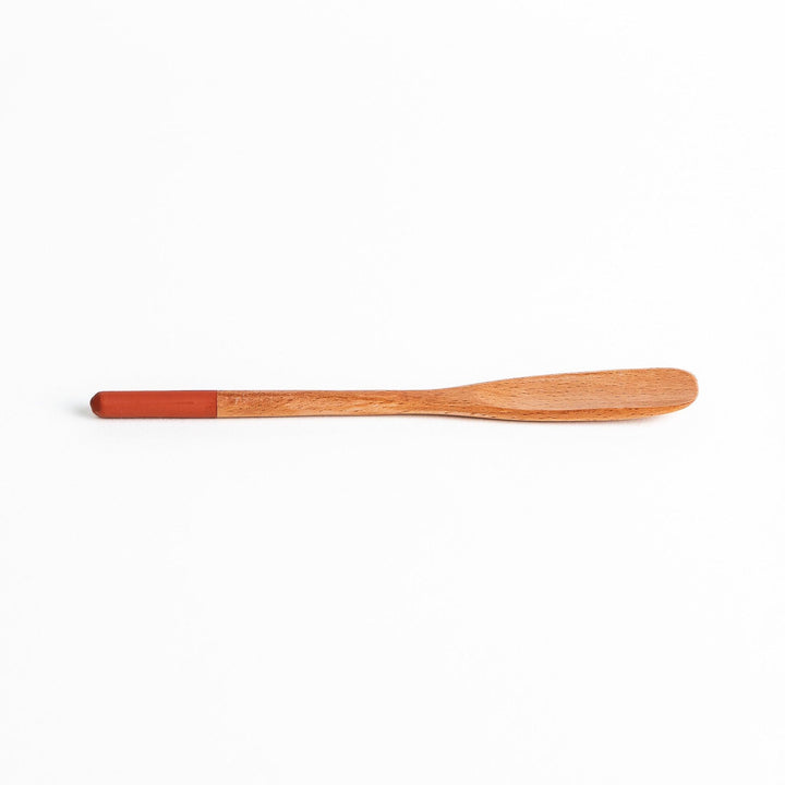 A set of four wooden spatulas with flat tips, each featuring a different colored end—white, black, blue, and red