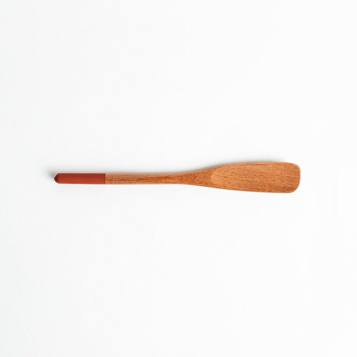 A set of four wooden spatulas with flat tips, each featuring a different colored end—white, black, blue, and red