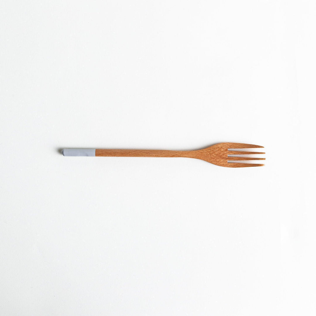 A set of four wooden pasta fork, each with a different colored tip—white, black, blue, and red.