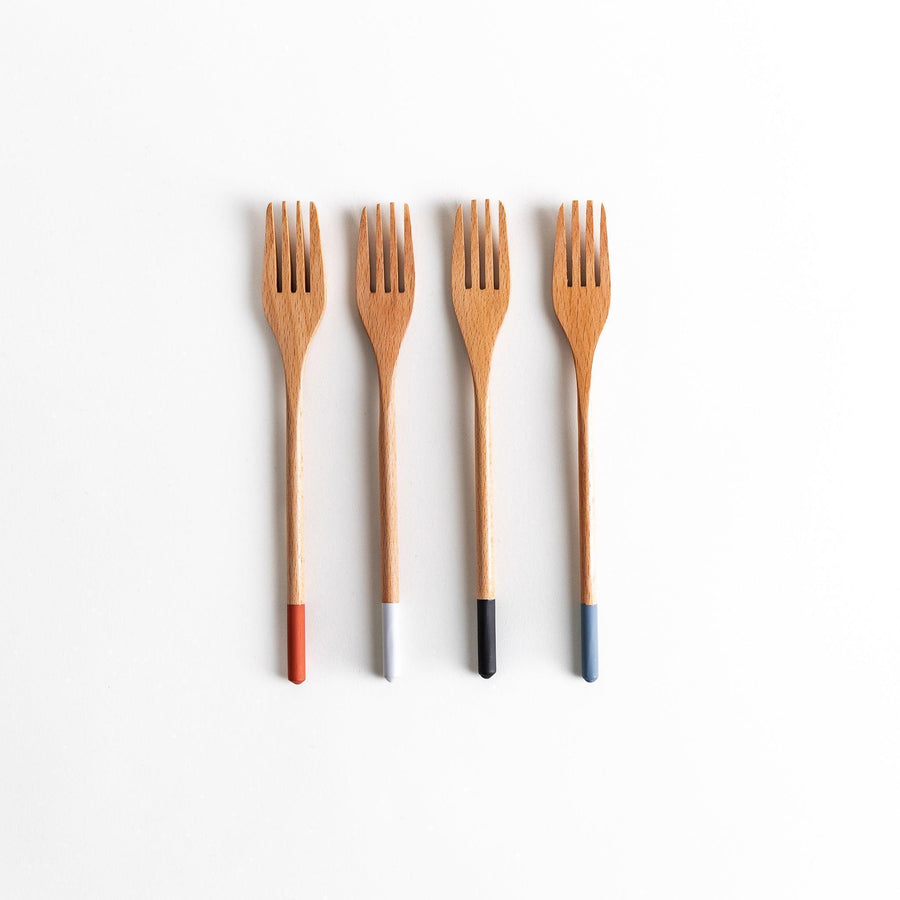 A set of four wooden pasta fork, each with a different colored tip—white, black, blue, and red.