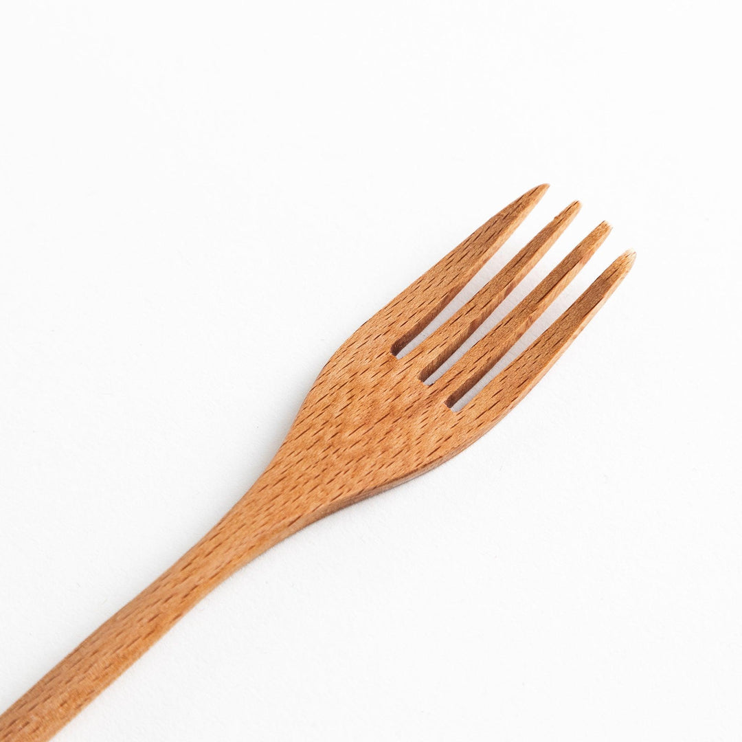 A set of four wooden pasta fork, each with a different colored tip—white, black, blue, and red.