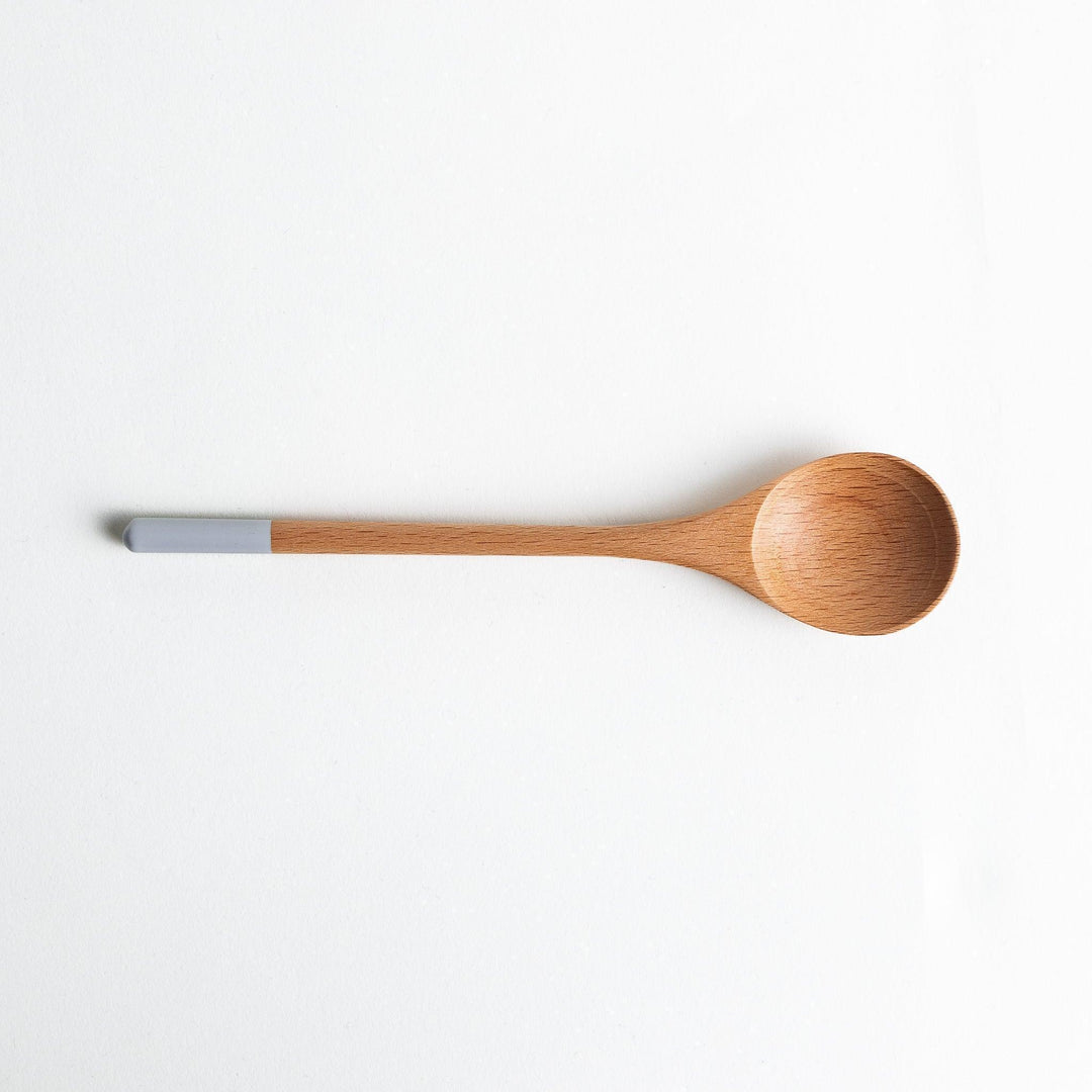 A set of four wooden soup spoons with wide, rounded bowls and colored tips—white, black, blue, and red.