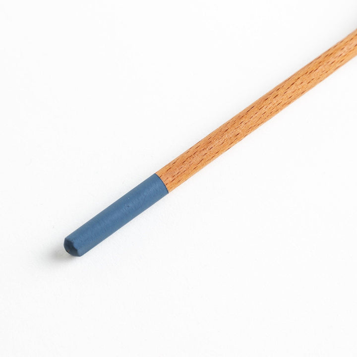 A set of four wooden soup spoons with wide, rounded bowls and colored tips—white, black, blue, and red.